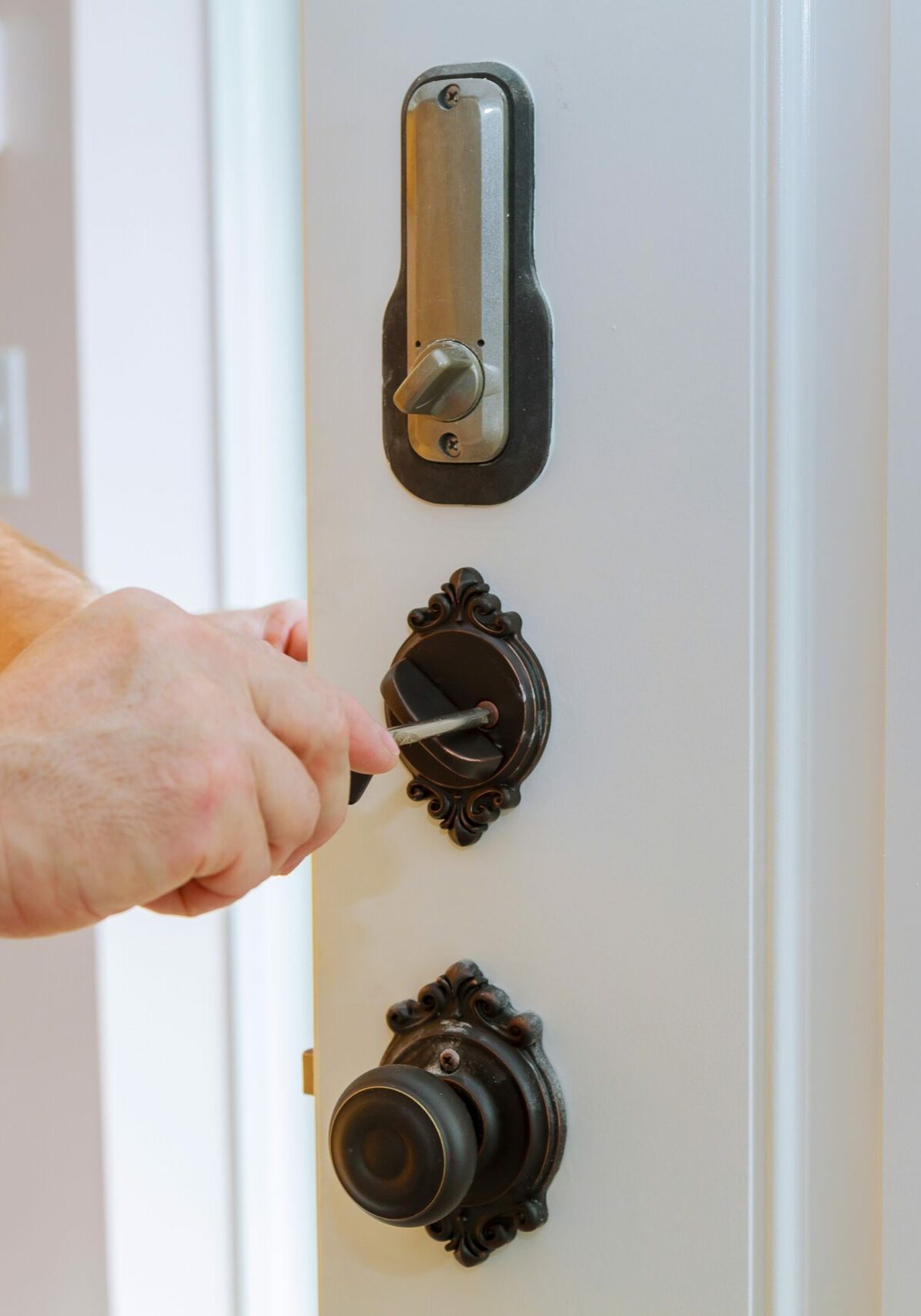 Closeup of a professional locksmith installing or repairing a new deadbolt lock on a house door with the inside internal parts of the lock visible.